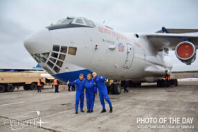 Participants in a zero-gravity flight against the backdrop of an Il-76MDK aircraft used for cosmonaut training.